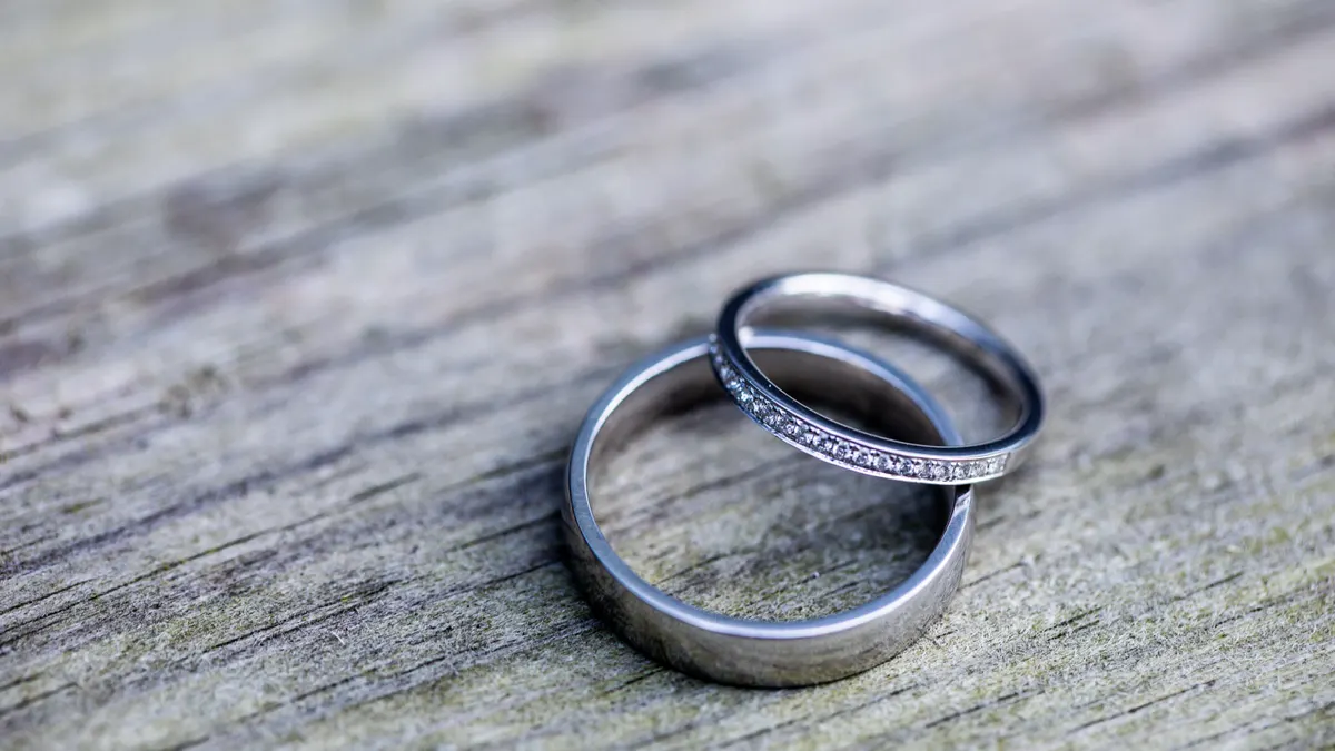 Gros plan d'alliances et bagues de fiançailles en argent, dont une sertie de diamants, sur bois rustique