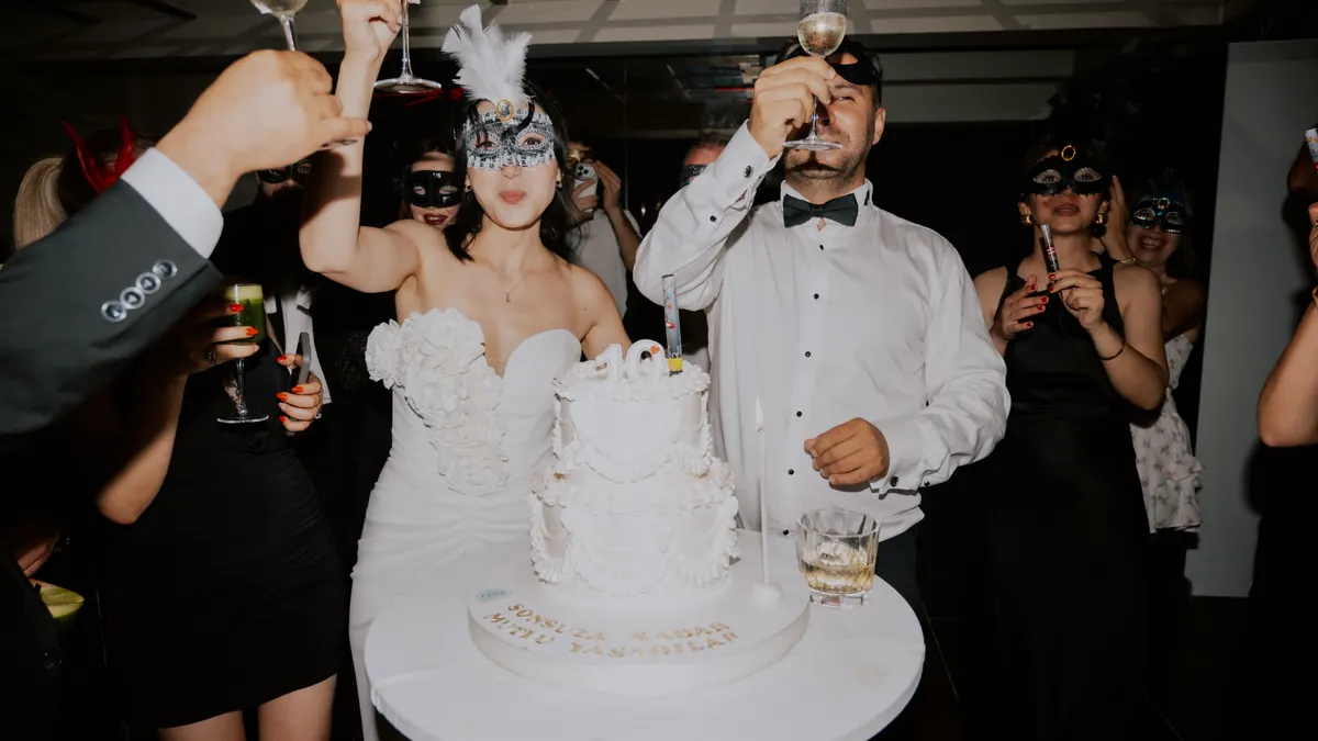 Mariage élégant sur le thème des masques, invités trinquant près d'un gâteau somptueux.